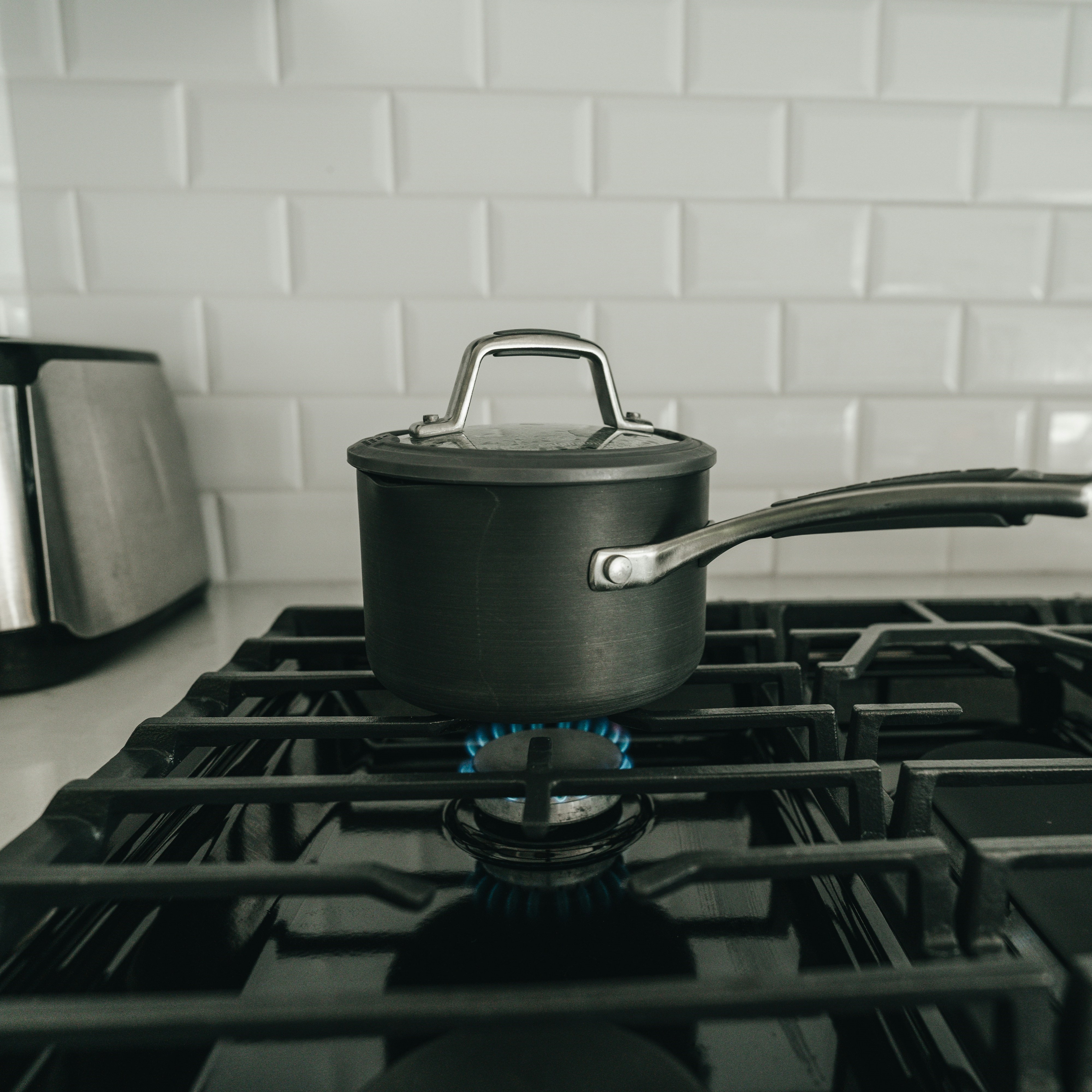 Photograph of a small saucepan on top of a lit gas stove